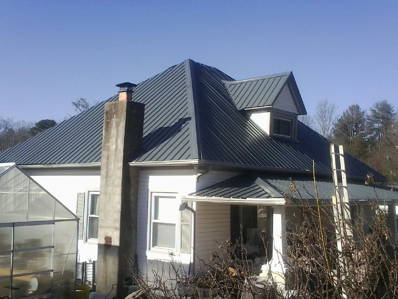 Dark blue standing seam metal roof on a white farmhouse with dormer — Slate & Tile Roof Repair by Roofing Brothers in Knoxville