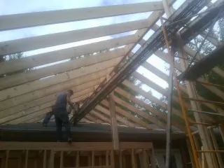 Rafters going up over a new addition with a worker on the wall in Knoxville