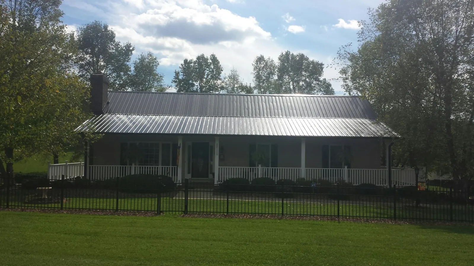 Gray metal roof on a brick ranch with a full width front porch — Gutter Guard Installation work by our crew in Knoxville