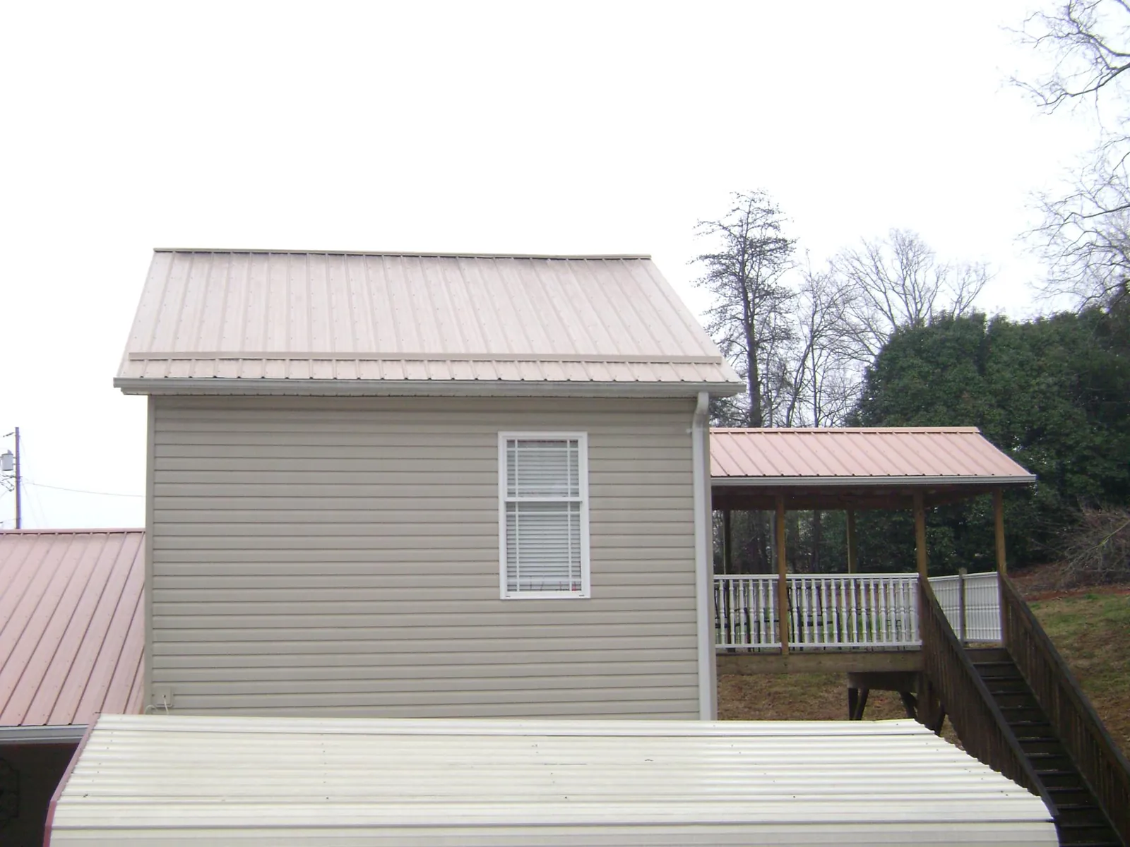 Tan metal roofs on a two story addition and attached porch, from a Roof Replacement job in Knoxville